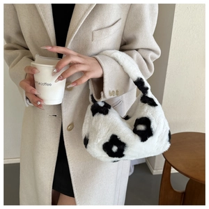 Dettaglio borsa di peluche bianco con fiori neri abbinata a un cappotto autunnale