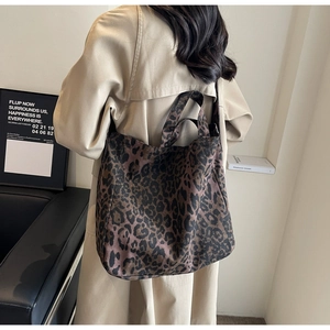 Detailed view of a leopard print tote bag styled by a model in a modern urban setting