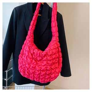 Detail of bright pink quilted puffer bag with wavy pleated texture on a black suit