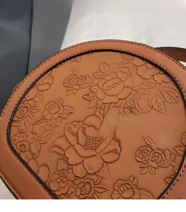 Close-up of embossed floral patterns on the premium brown leather crossbody bag