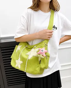 Détail du sac cabas en velours côtelé vert avec étoiles blanches porté par le mannequin