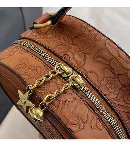 Detail of floral embossed PU leather bag with gold double zipper and star charm pendants