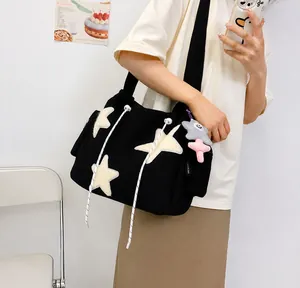 Détail du sac cabas en toile noire avec patchs d'étoiles blanches et cordon de serrage