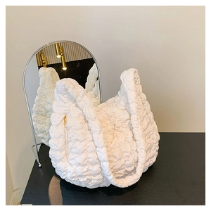 Detail of white quilted cloud bag with 3D pleated texture and gold side zipper detail