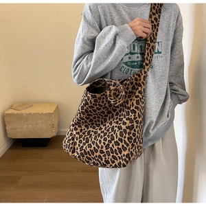 Detail of trendy leopard print canvas crossbody bag with wide shoulder strap on model