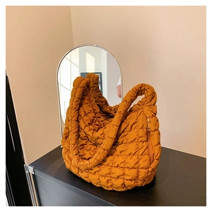 Detailed view of ginger yellow quilted dumpling bag with metallic zipper and texture
