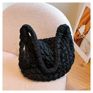 Detail of black cloud-quilted tote bag featuring soft puff pleats and side zipper texture