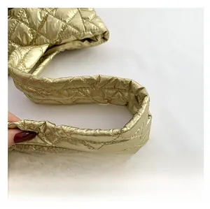 Detail shot of the golden quilted handle with precise stitching on a chic handbag