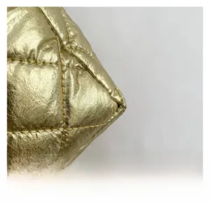 Macro detail of golden metallic quilted fabric with elegant rhombic patterns and stitching