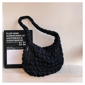 Detailed close-up of a black puffy cloud bag showing quilted nylon texture and gold zipper