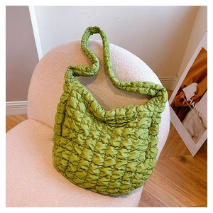 Close-up of vibrant green puffy quilted shoulder bag texture and ruched strap details