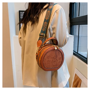 Detail of round caramel PU bag featuring 3D floral embossing and woven boho strap