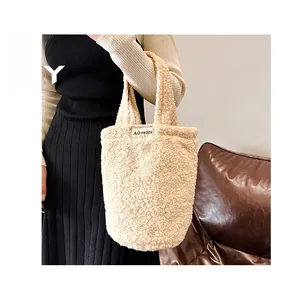 Detail view of beige plush teddy tote bag with woven label shown in lifestyle setting
