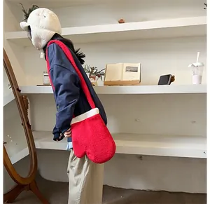 Dettaglio della creativa borsa a tracolla in peluche rosso a forma di guanto con bordo in pelliccia