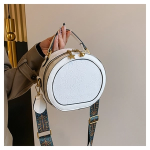 Close-up of white PU handbag featuring floral embossing and ethnic style wide strap