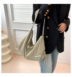 Close-up of sage green hobo bag featuring pleated texture and Superior brand label