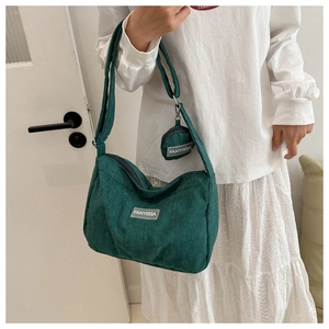 Dettaglio borsa a tracolla in velluto a coste verde scuro con tracolla larga e mini pouch