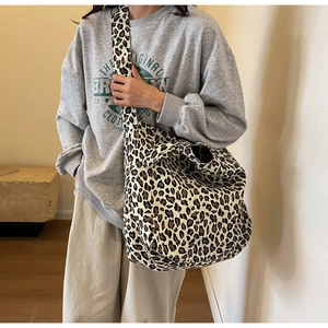 Detailed view of leopard print canvas tote bag with wide shoulder strap on model