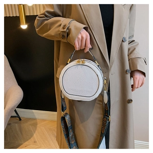 Detail of white PU leather round bag with floral relief and vintage blue woven strap