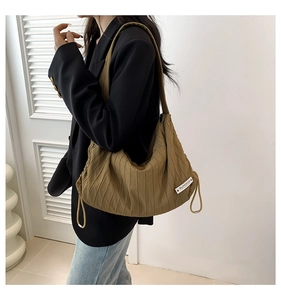 Detailed macro view of khaki pleated nylon tote bag with drawstring and brand label detail