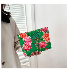 Detail of vibrant green nylon clutch featuring traditional red peony and phoenix patterns