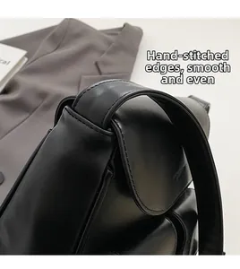 Detail of high-quality manual stitching on smooth black leather shoulder bag surface