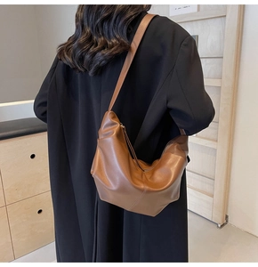 Dettaglio della borsa a spalla marrone plissettata indossata da una modella