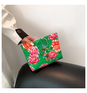 Detail of green clutch bag featuring vibrant peony patterns and phoenix embroidery