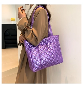 Detail view of large purple metallic quilted tote bag worn on a shoulder