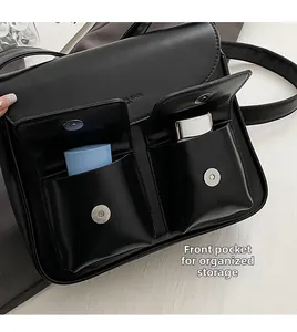Detail of minimalist black PU shoulder bag with dual front pockets and magnetic closures