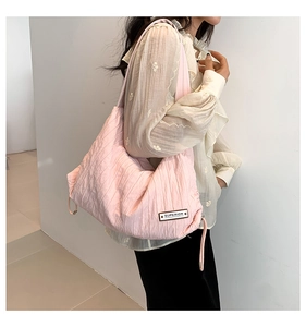 Detailed view of pink textured nylon tote bag with drawstring sides and logo patch
