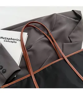 Detail of comfortable brown leather shoulder strap on a black nylon tote bag