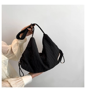 Detail of black pleated hobo bag featuring side drawstring and white logo tag