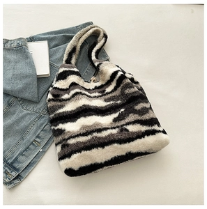 Close-up of soft faux fur tote bag with abstract black and white wavy zebra patterns