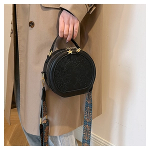 Detailed view of black PU leather round bag with floral embossing and star pendant