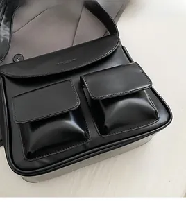 Close-up of black PU leather shoulder bag with double front pockets and stitching details
