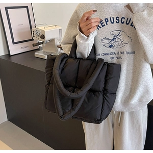 Detailed view of black quilted down tote bag with soft padded handles for winter