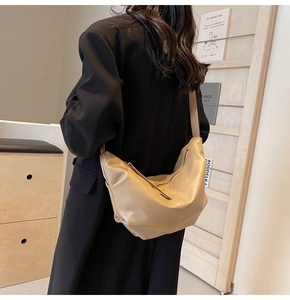 Dettaglio borsa hobo: morbida pelle beige e spaziosa forma a mezzaluna indossata dal modello