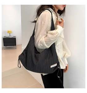 Close-up of black quilted shoulder bag featuring vertical pleated texture and side drawstring