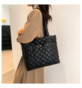 Quilted black puffer tote bag shown on a model to demonstrate large size and soft texture
