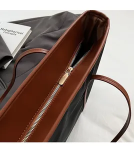 Detail of high-quality golden metal zipper and brown leather trim on black nylon tote bag