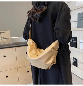 Vista laterale della borsa a tracolla beige a mezzaluna in morbida pelle con grande capienza