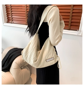 Detailed view of cream-colored oversized dumpling bag with pleated texture on the shoulder