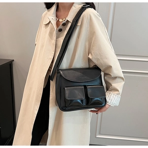 Close-up of black leather crossbody bag with dual front pockets and adjustable strap