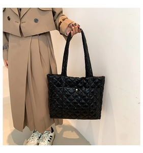 Detail of a black quilted puffer tote bag with silver button pocket and nylon texture