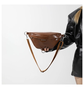 Close-up of caramel brown PU leather crossbody bag with silver hardware and fashion label