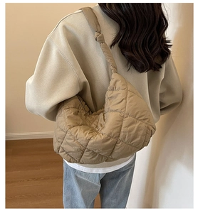 Side view of khaki quilted shoulder bag with knot strap detail on a casual outfit