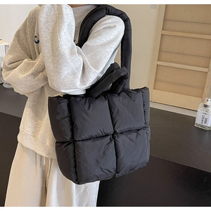 Detail of a black quilted down tote bag showing high-capacity design and nylon texture