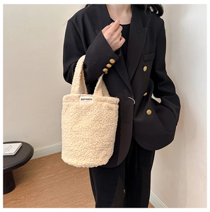 Detail of plush off-white fleece handbag with rectangular logo label shown on model
