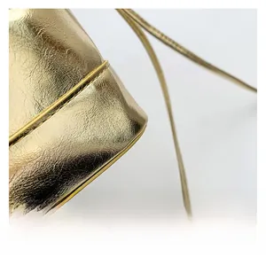 Close-up of golden metallic textured PU leather handbag with elegant pleated details
